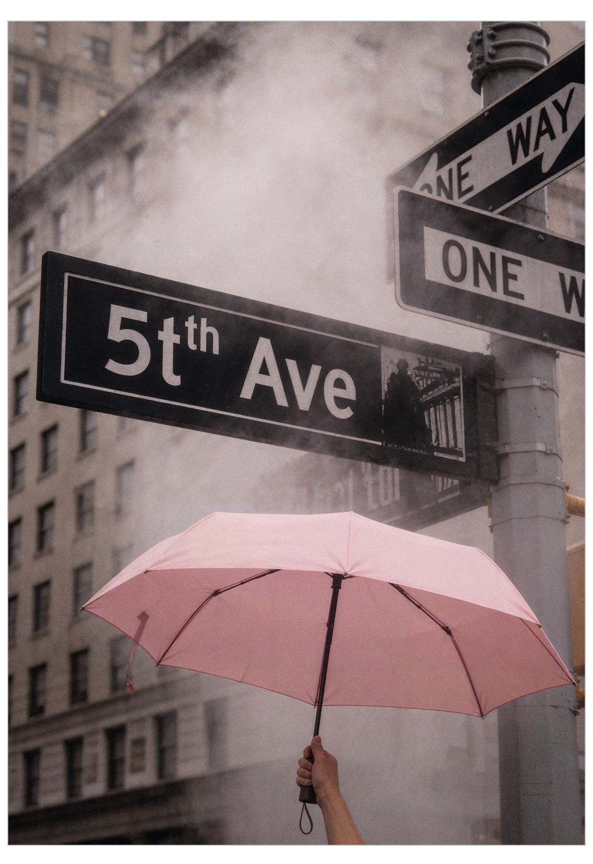 Pink umbrella held by a person at a street corner with '5th Ave' sign in the background