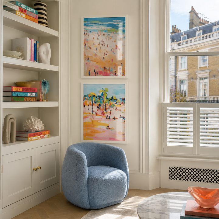 Modern living room with a blue armchair, bookshelf, and colorful artwork.
