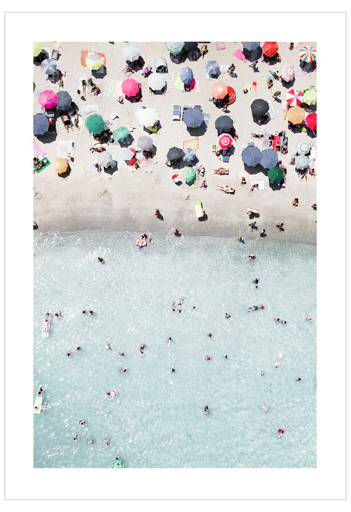 Top-down view of people on a beach with umbrellas and towels.