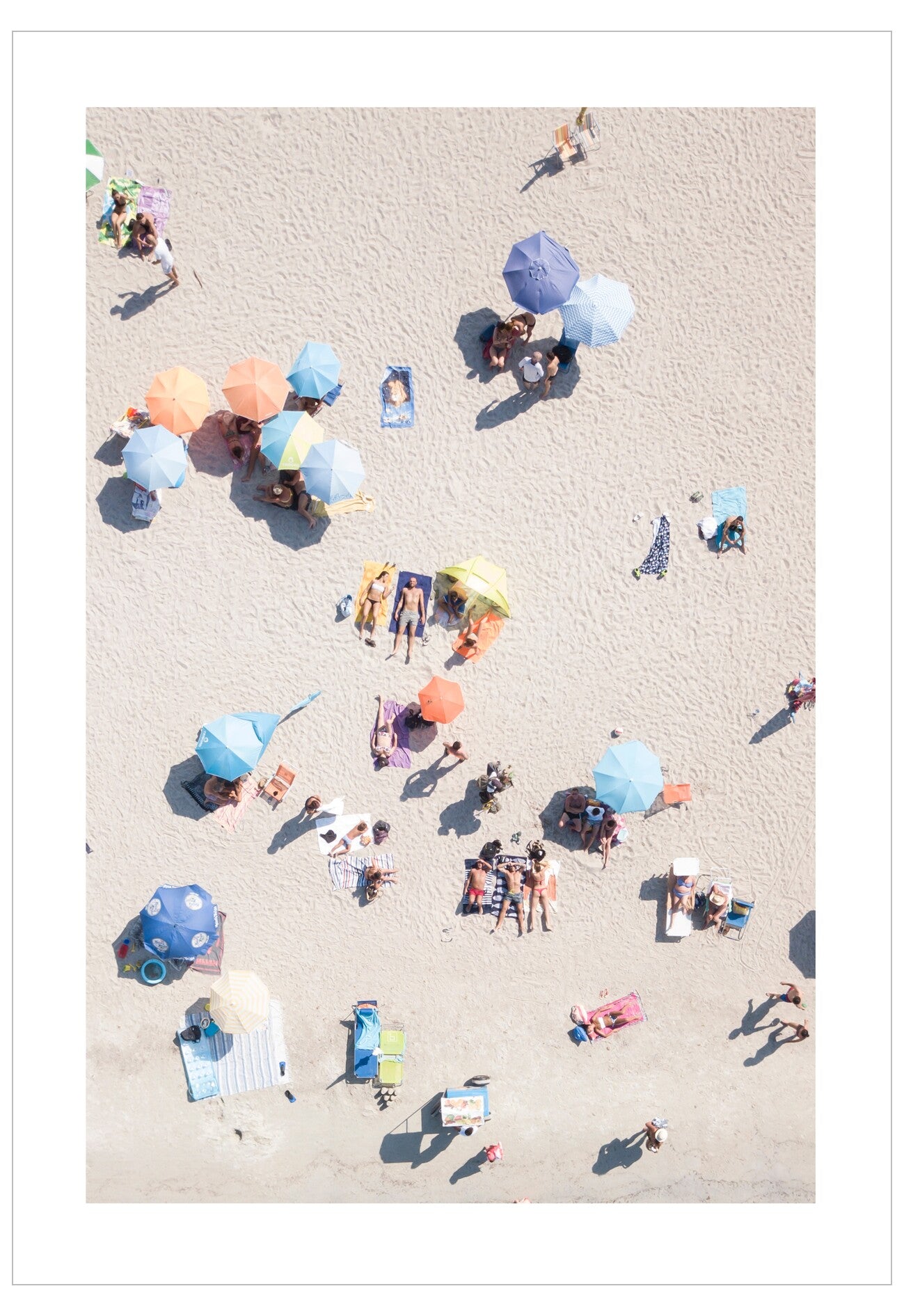 Top-down view of people on a beach with colorful umbrellas.
