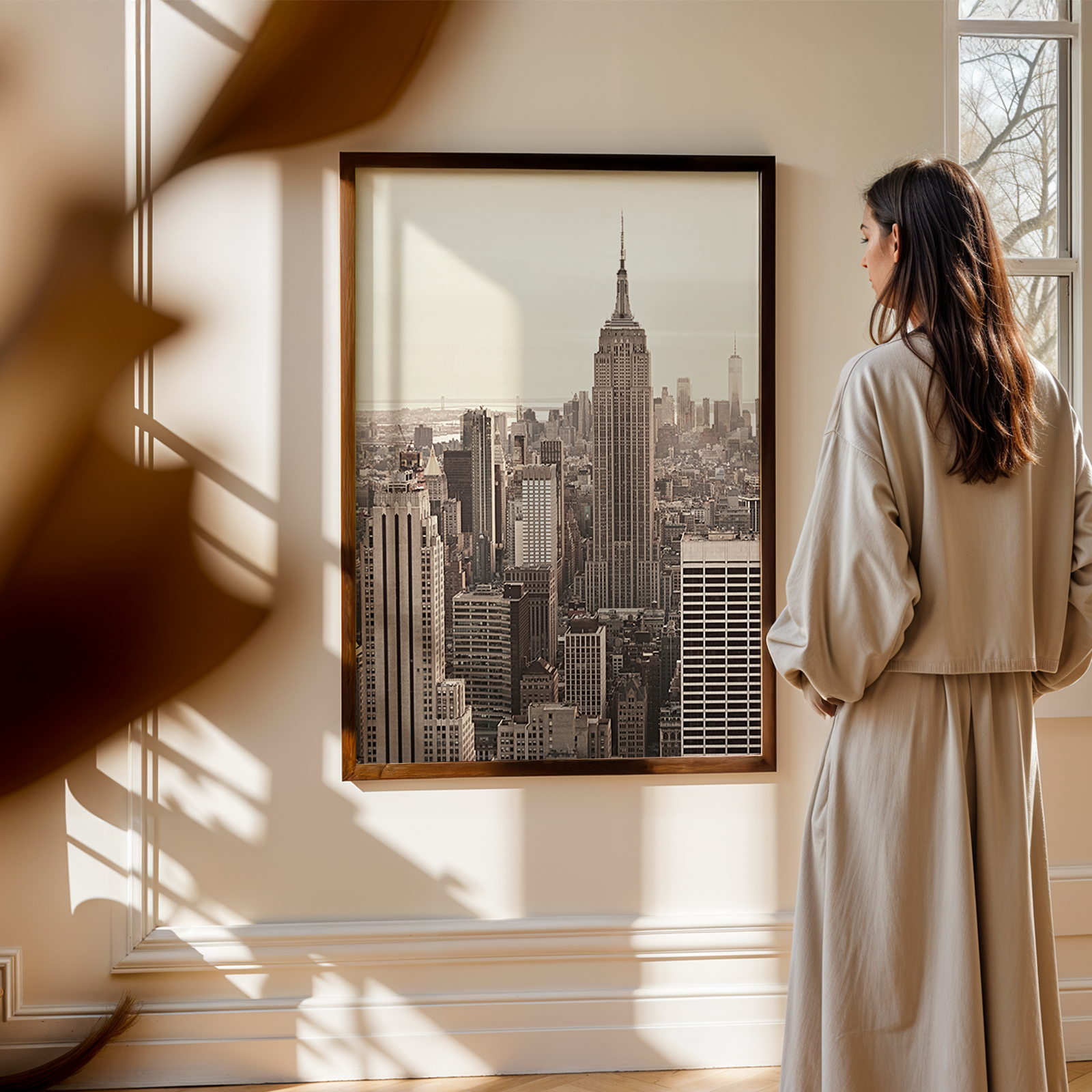 Woman standing in a room with a large framed picture of a city skyline on the wall.