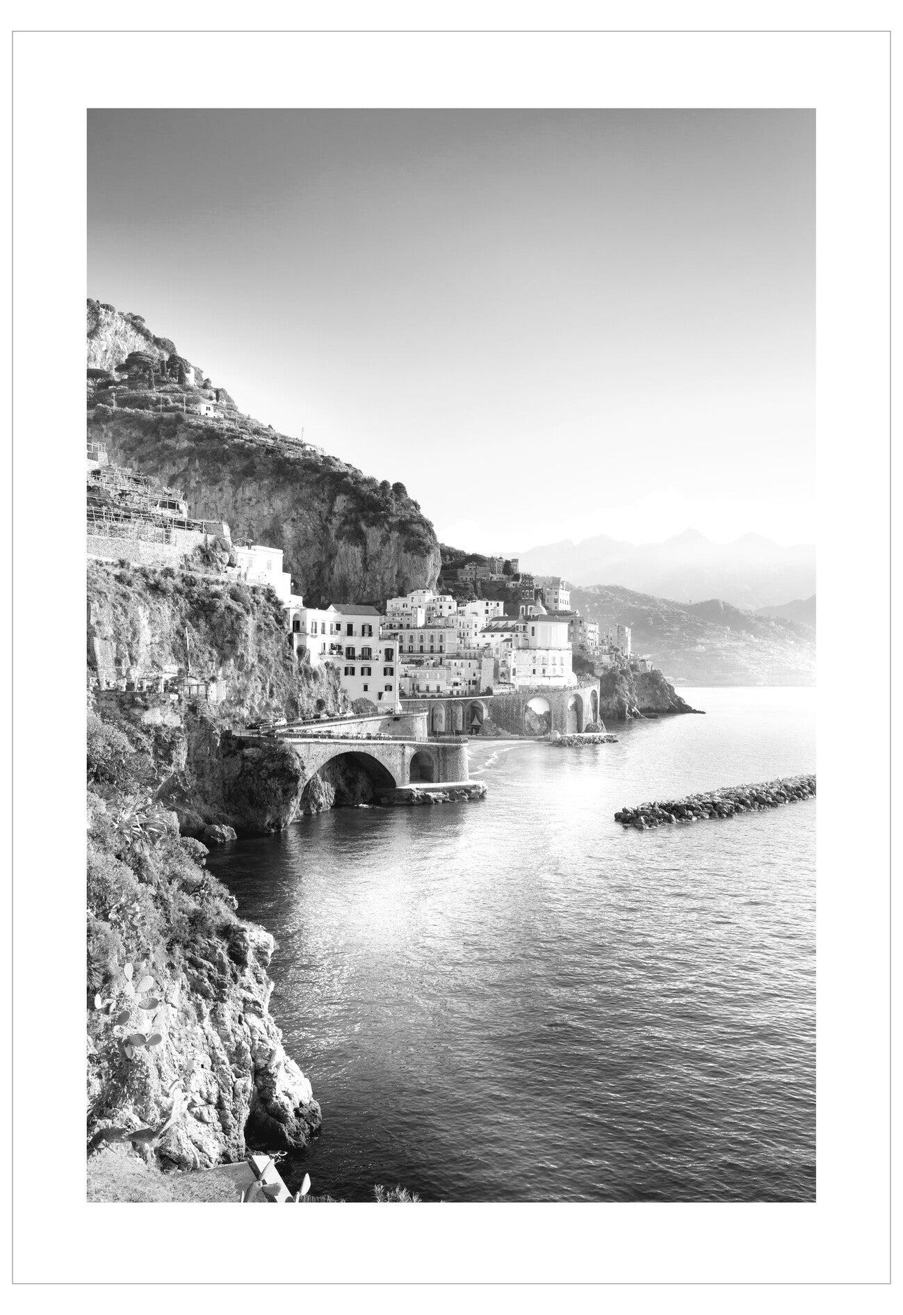 Black and white coastal scene with buildings on a cliff overlooking the sea.