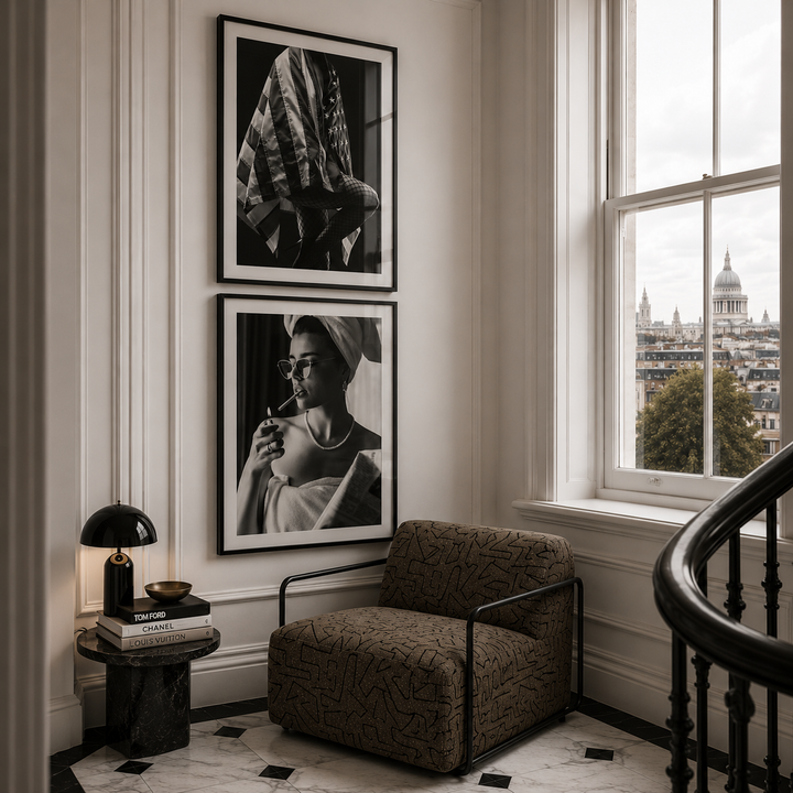 Modern interior with a brown armchair, side table, and framed pictures on a wall with a window view.