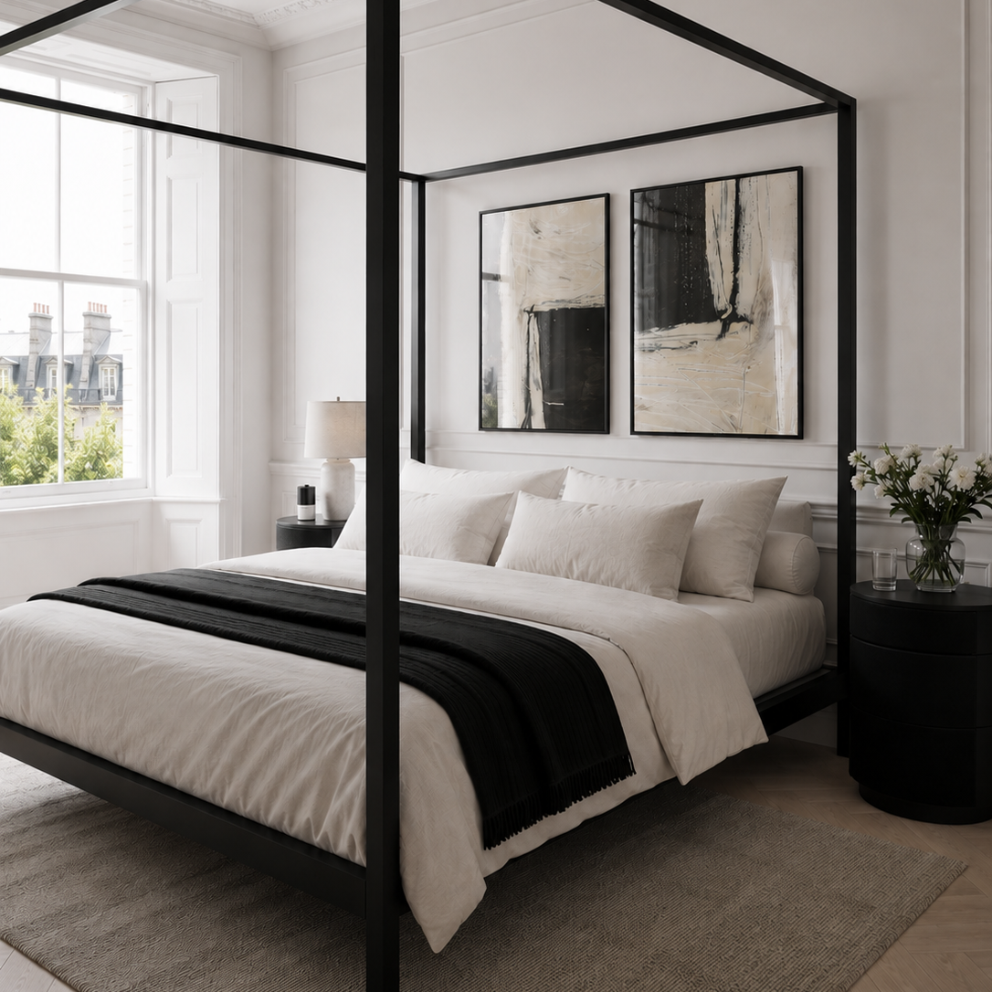 Modern bedroom with a black canopy bed and white bedding.