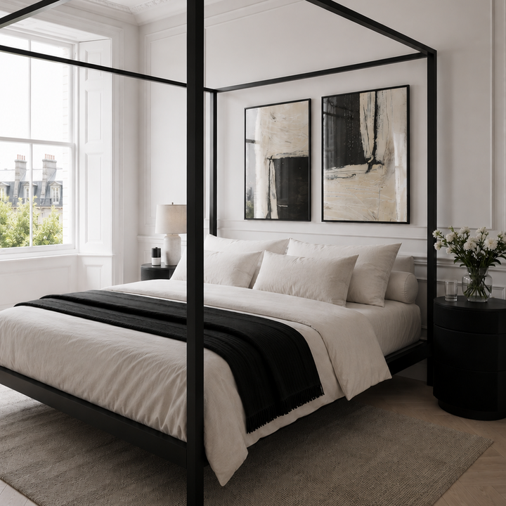 Modern bedroom with a black canopy bed and white bedding.