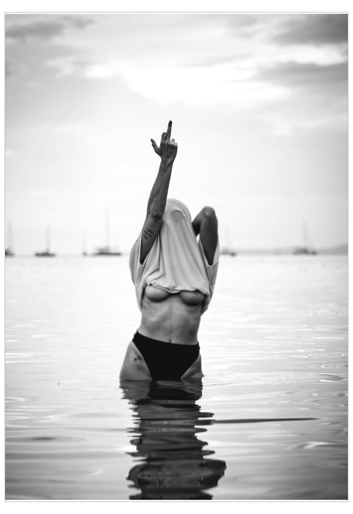Person in a hijab standing in water with one arm raised, black and white photo