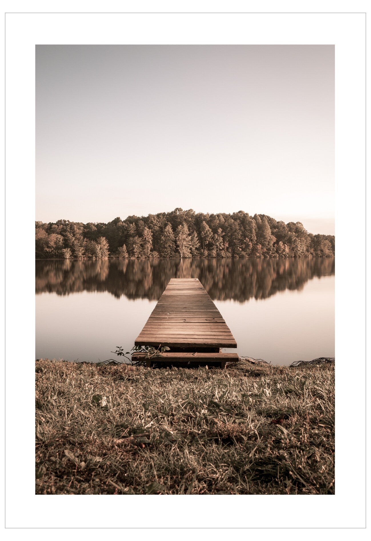 Wooden dock extending into a calm lake with trees reflecting on the water.
