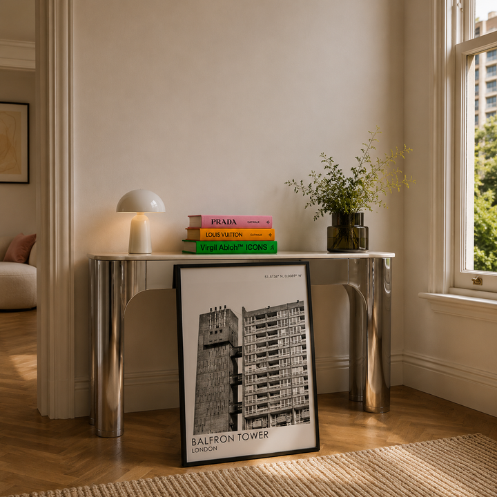 Modern interior with a console table, books, and a framed picture in a well-lit room.