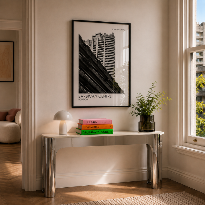 Modern interior with a table, books, and a framed picture of the Barbican Centre.