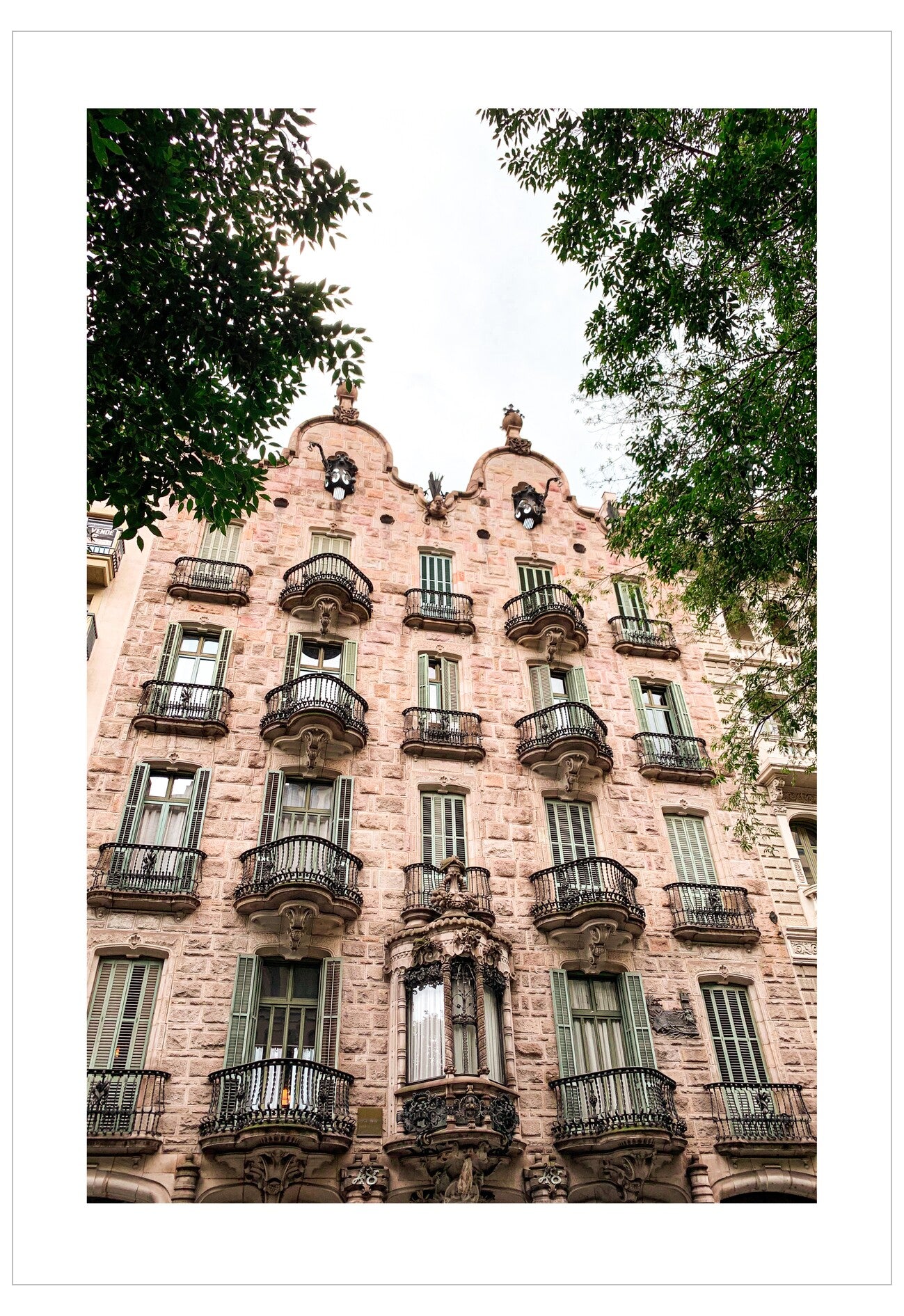 Detailed facade of a building with decorative elements and balconies, surrounded by trees.