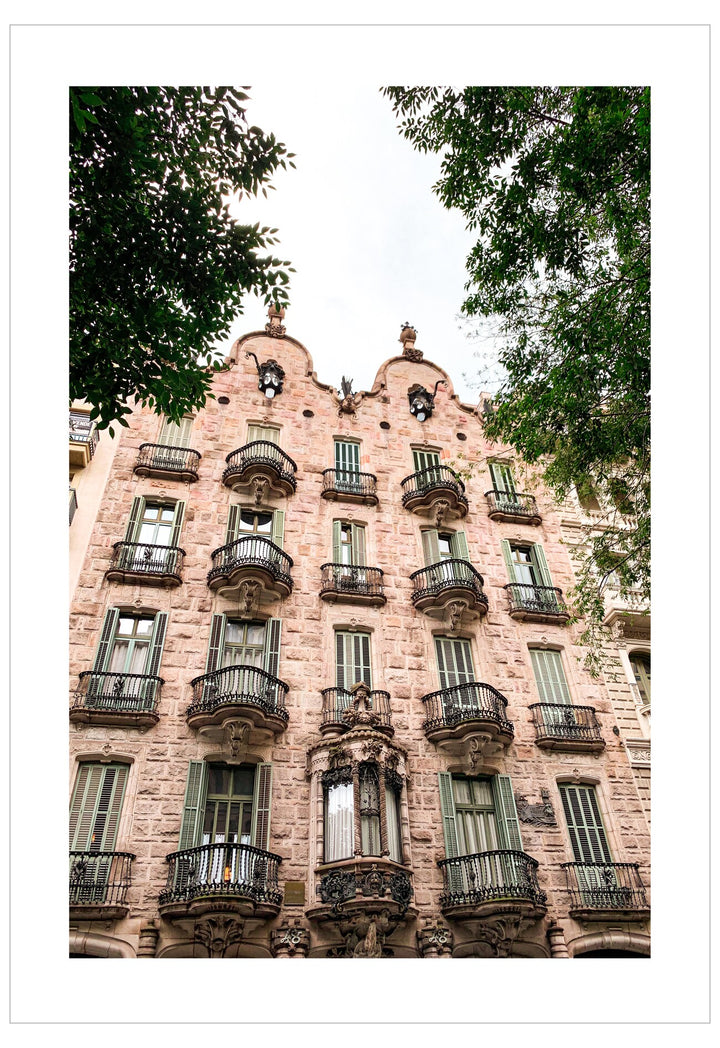 Detailed facade of a building with decorative elements and balconies, surrounded by trees.