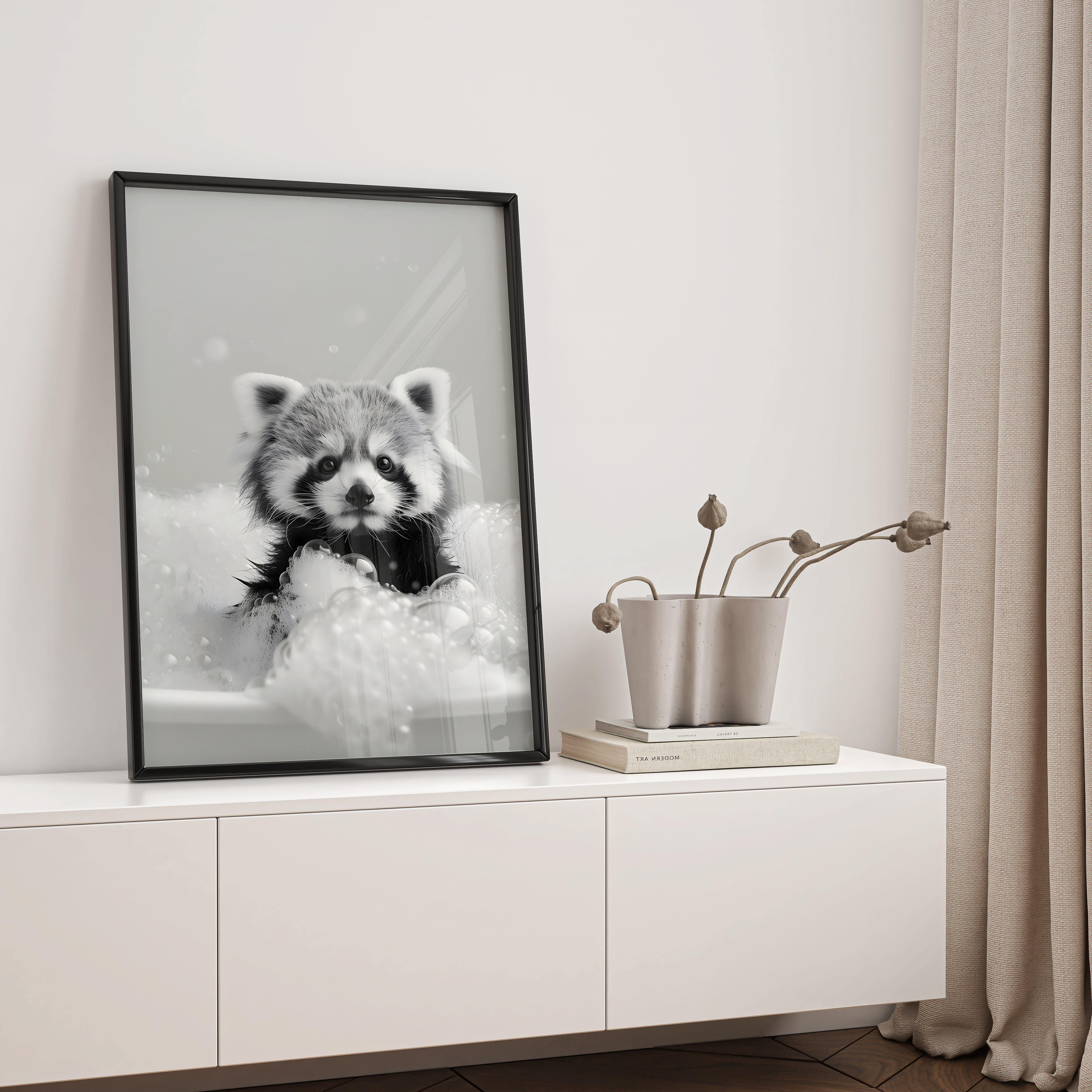 Framed black and white raccoon print on a white wall above a white cabinet with decorative items.