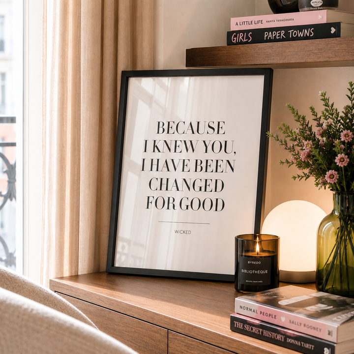 Framed quote on a wooden shelf with books and a candle