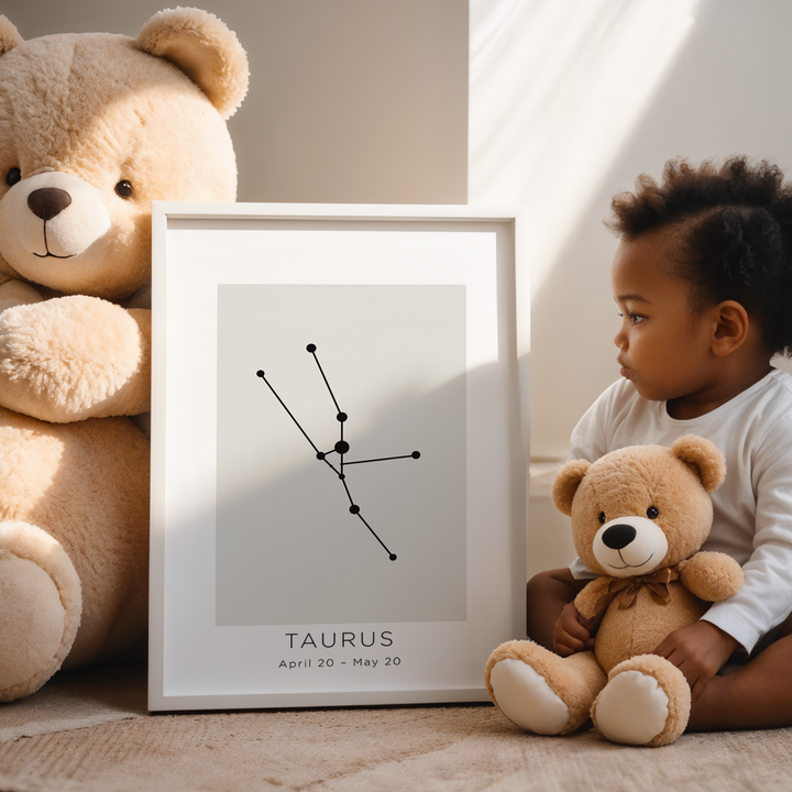 Child holding a teddy bear next to a framed Taurus zodiac sign on a carpeted floor.