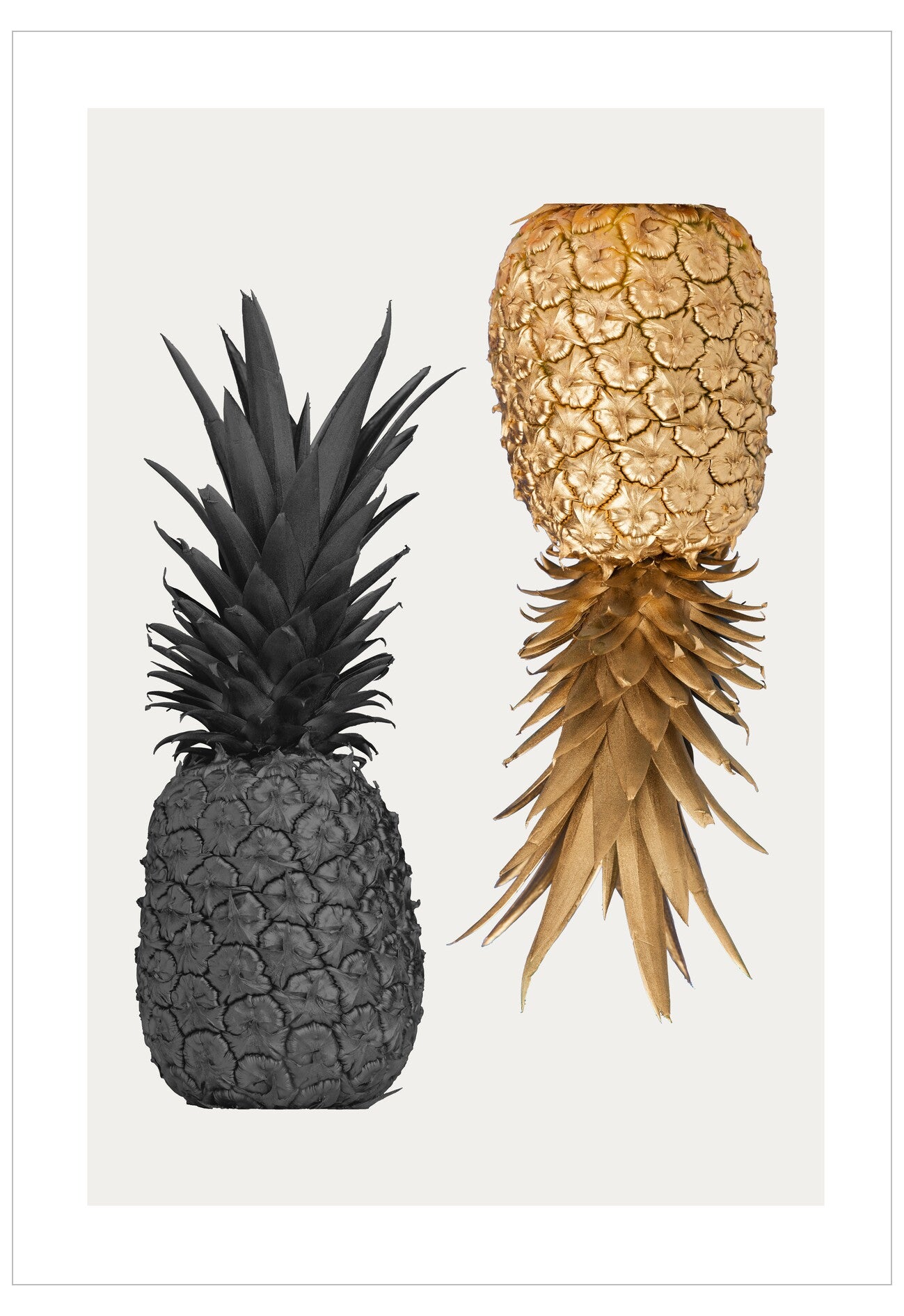 Two pineapples, one black and one gold, on a white background