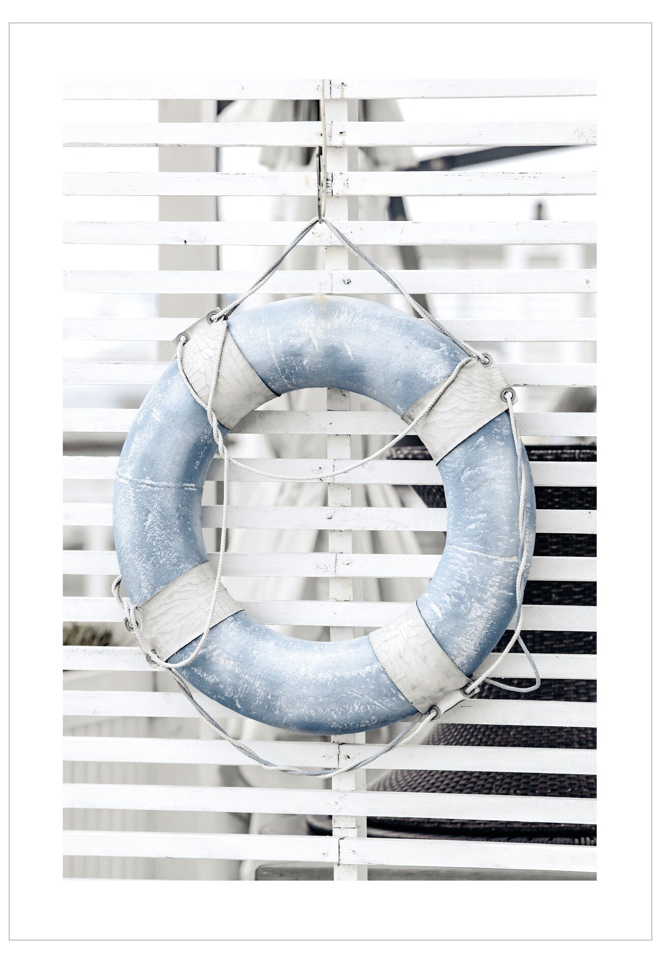 Blue life buoy hanging on a striped white and gray wall