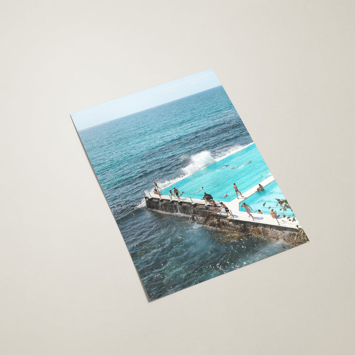 Poster of a coastal scene with people on a pier and blue ocean.