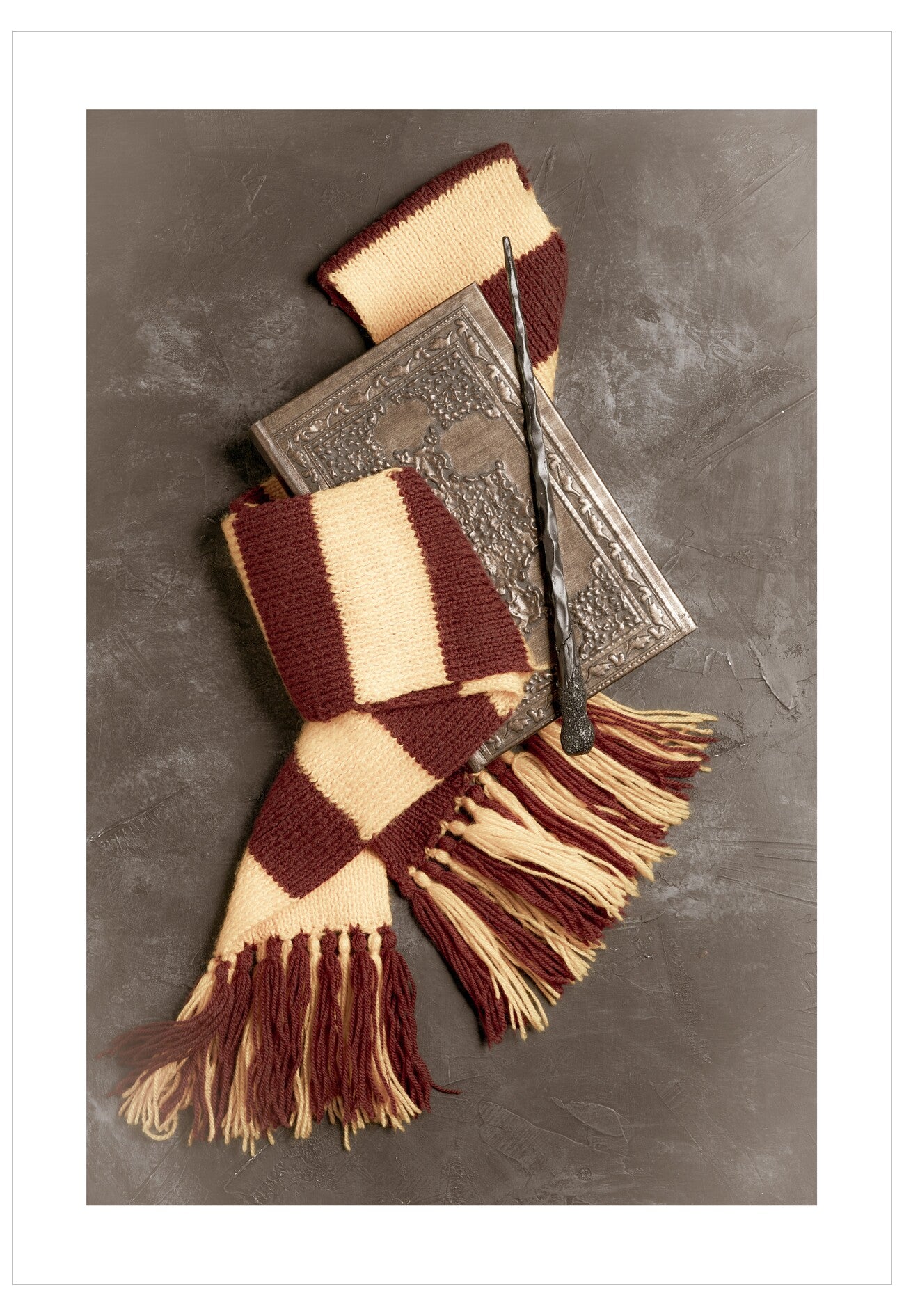 Hogwarts scarf with broom and book on a textured surface