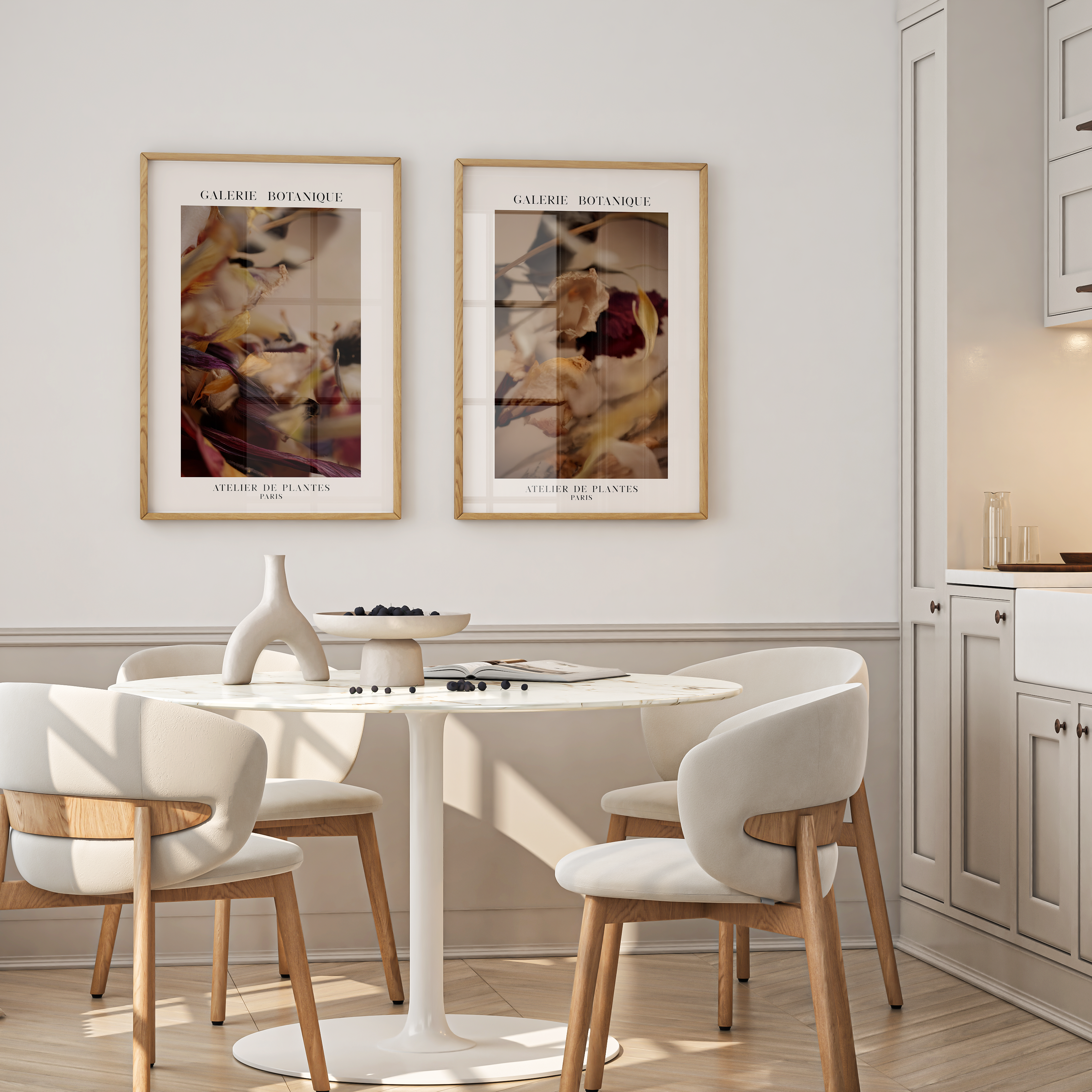Dining area with a round table and chairs, framed art on the wall, and kitchen cabinets.