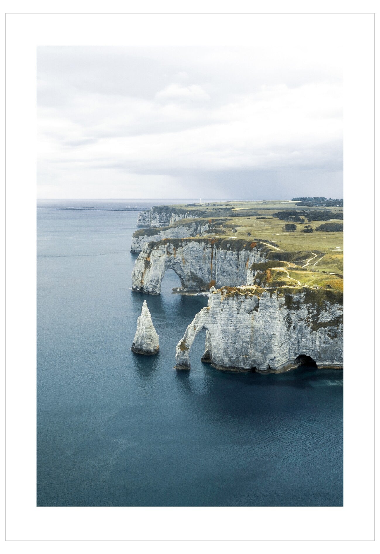 White cliffs of a coastal landscape with blue water and green fields.