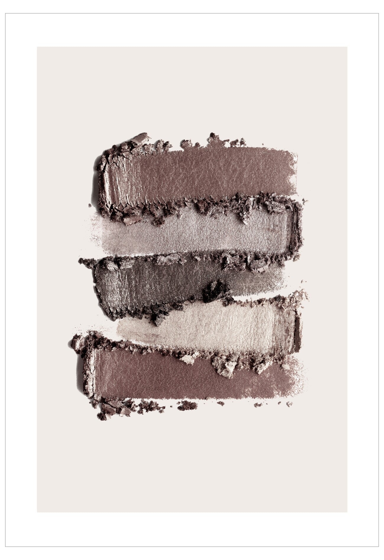 Stack of brown and gray eyeshadow swatches on a light background