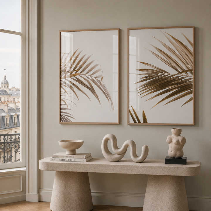 Decorative setup with framed palm leaf prints, sculptures, and a small statue on a console table.