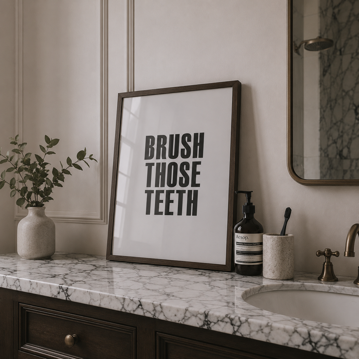 Bathroom counter with a framed poster, plant, and sink.