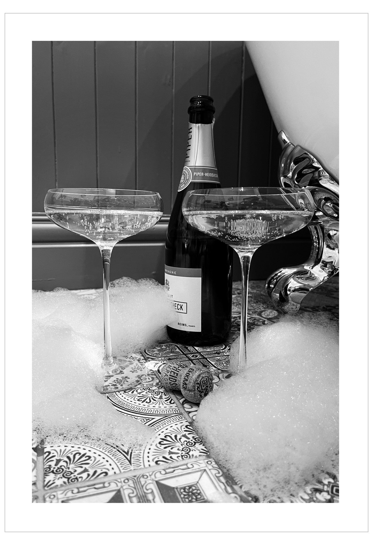 Bottle of champagne with two glasses on a decorative tablecloth with bubbles.