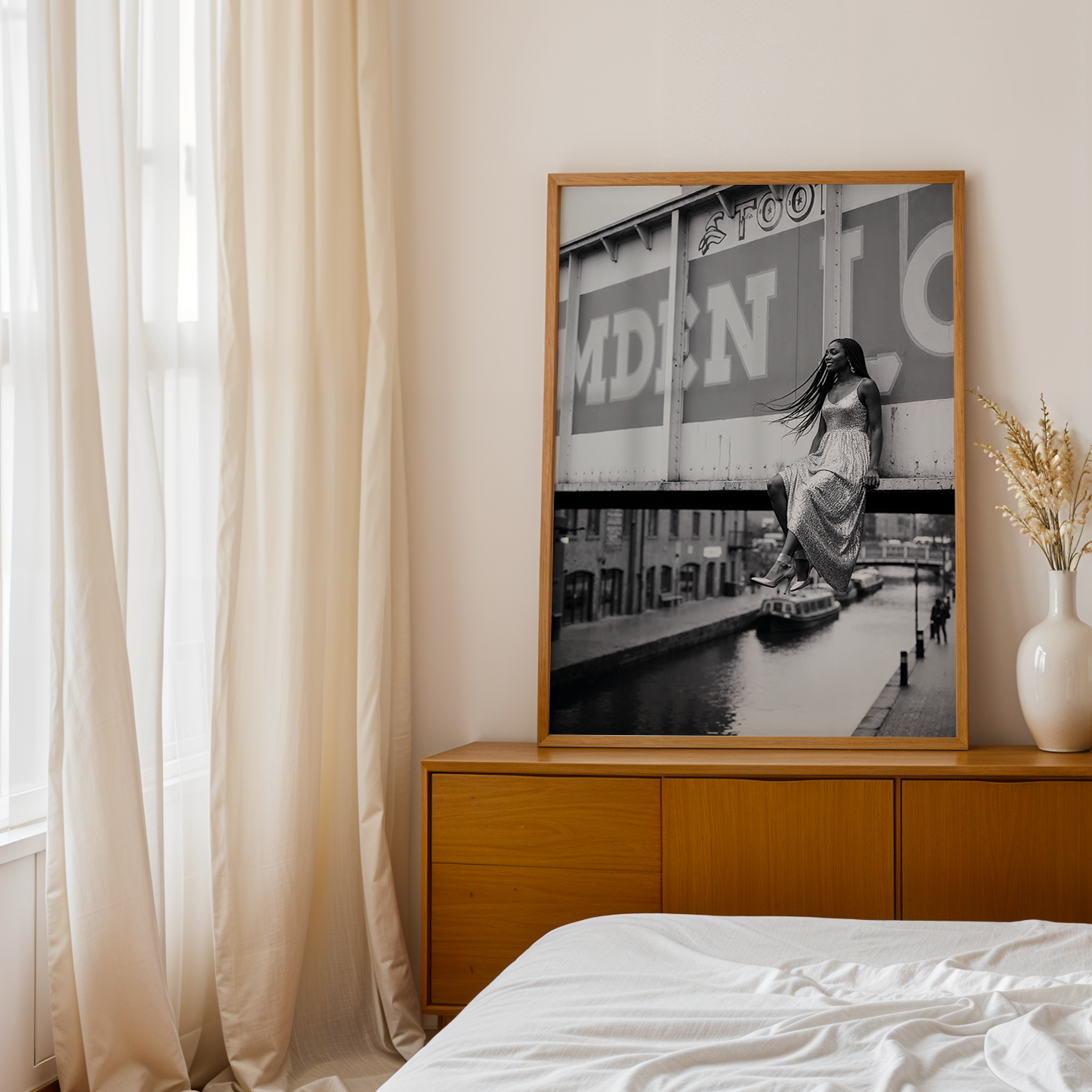 Wooden dresser with framed artwork and decorative vases in a bedroom setting.