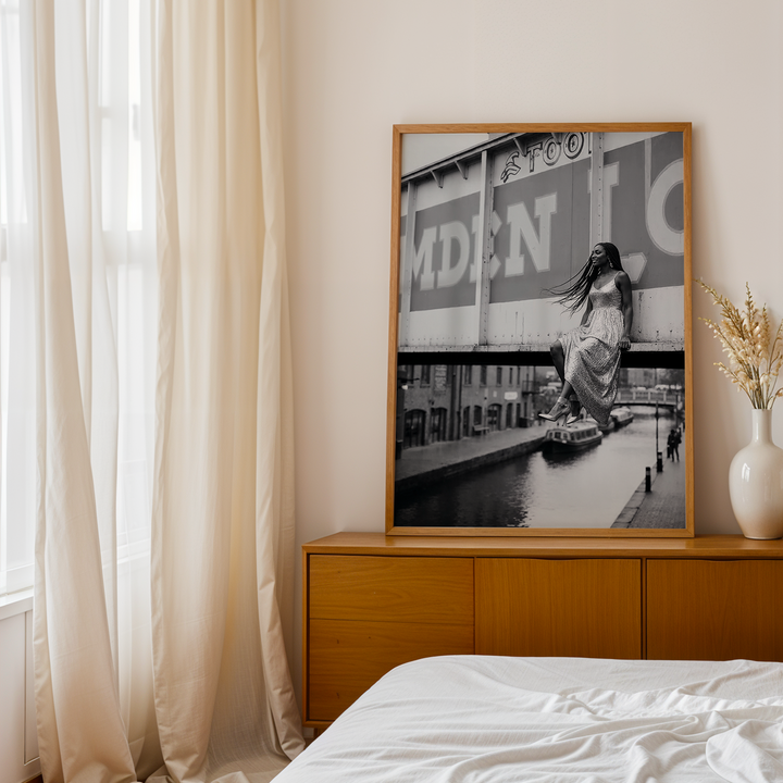 Wooden dresser with framed artwork and decorative vases in a bedroom setting.