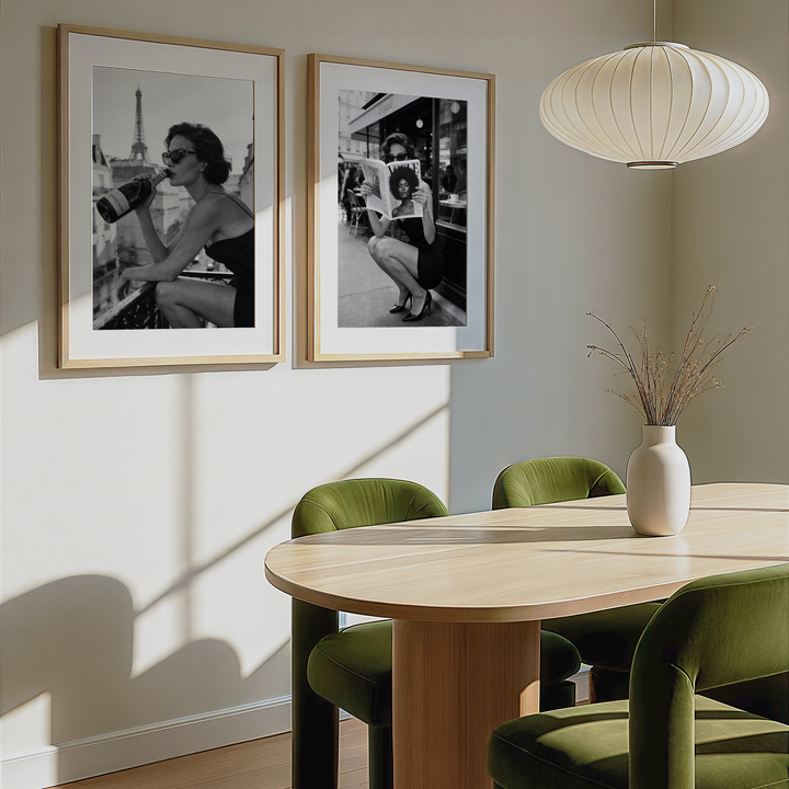 Dining room with wooden table, green chairs, and framed black and white photos on the wall.