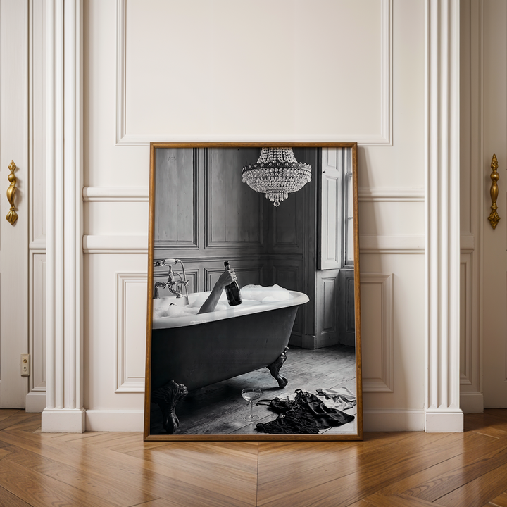 Framed black and white artwork of people on surfboards in a room with wooden floor and white walls.