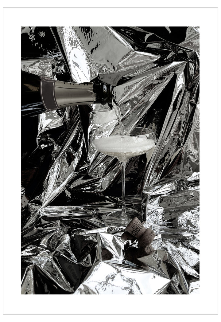 Cocktail glass with a straw on crumpled silver foil