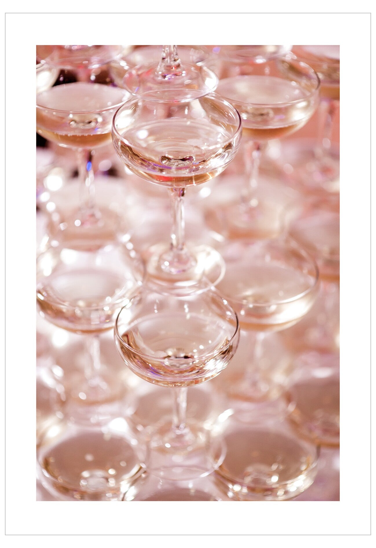 Row of champagne glasses with a pinkish tint on a white background