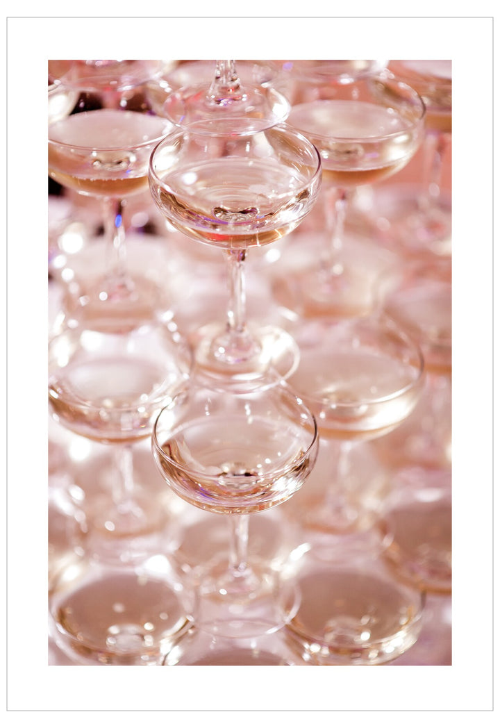Row of champagne glasses with a pinkish tint on a white background