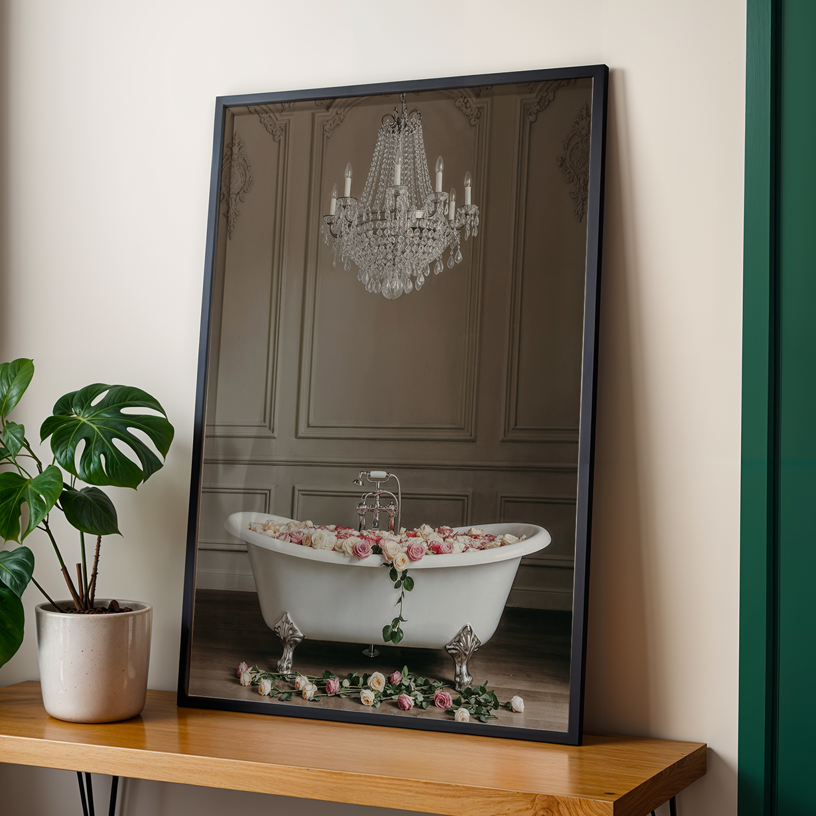 Framed photograph of a chandelier and bathtub on a wooden shelf with a plant next to it.