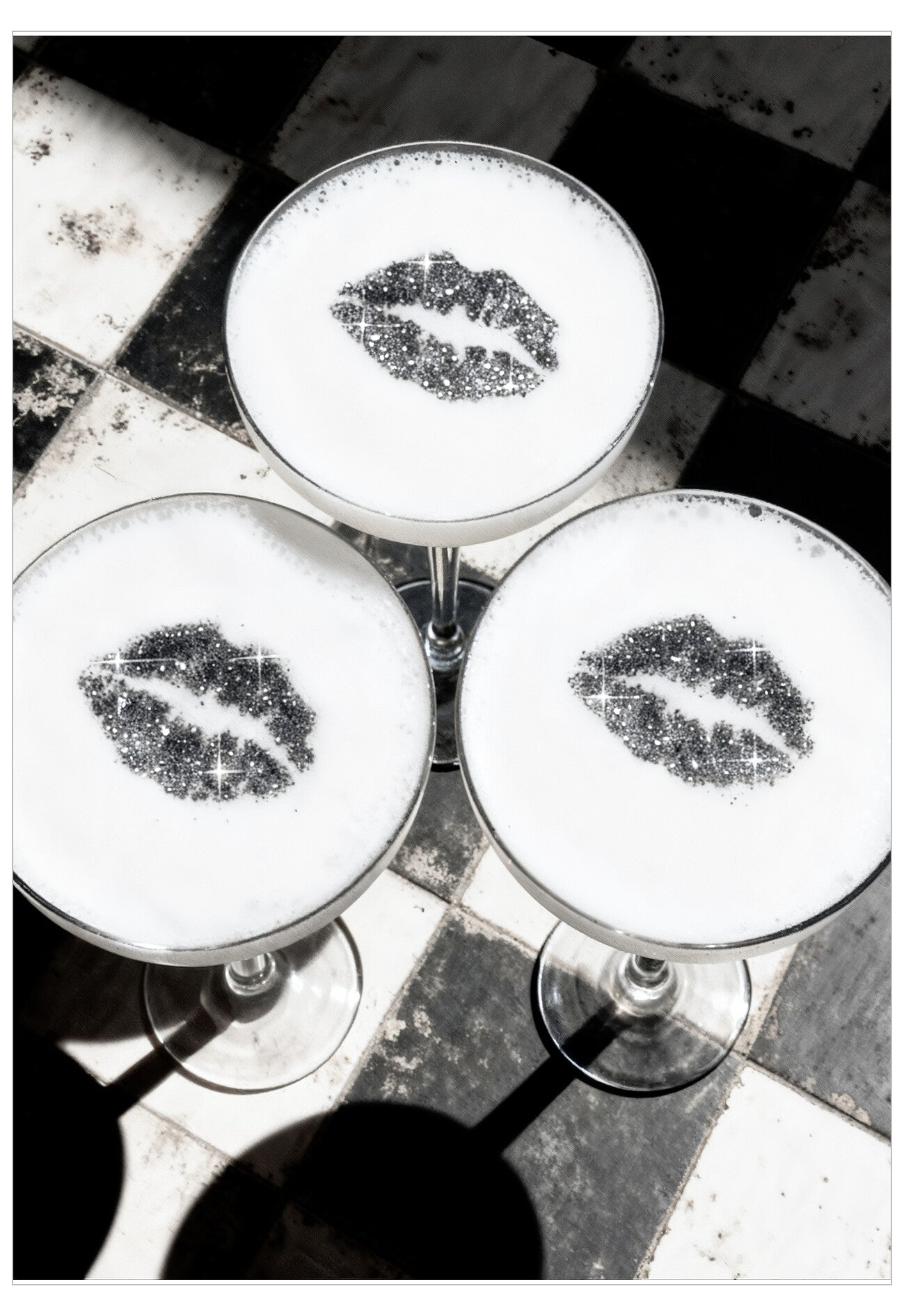 Three cocktails with lip-shaped foam art on a checkered floor.