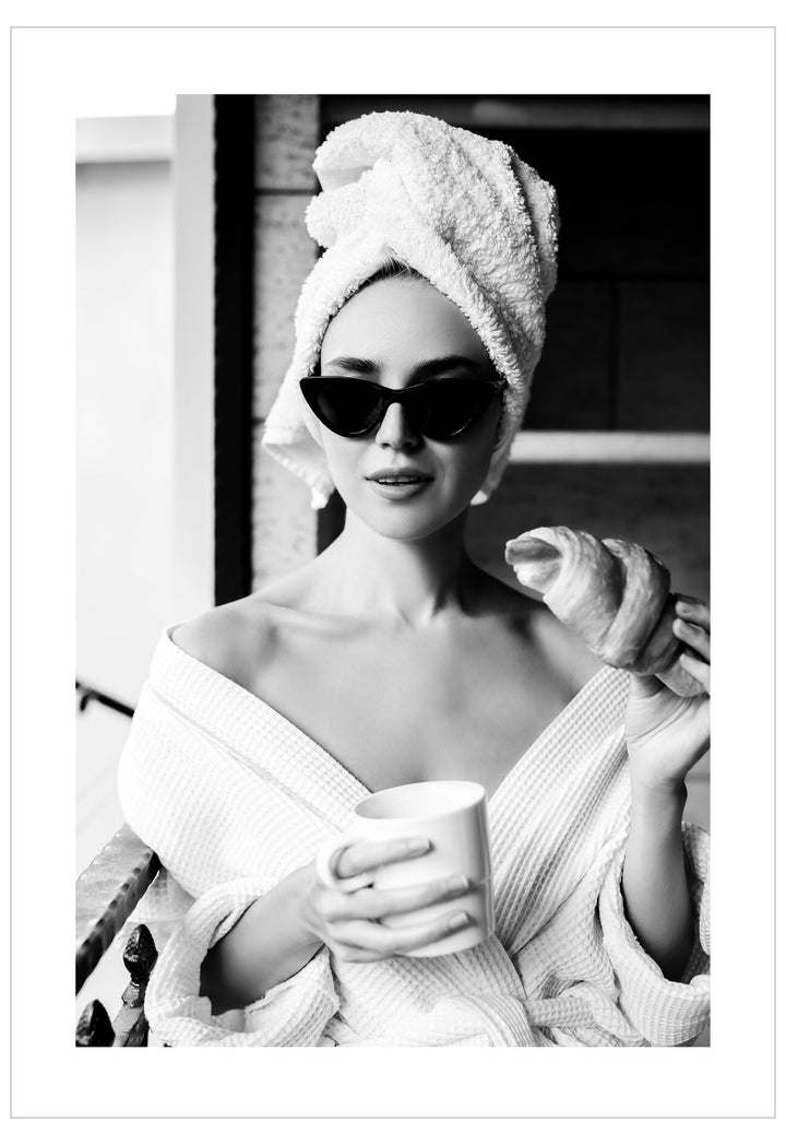 Black and white photo of a woman with a towel wrapped around her head, holding a cup.