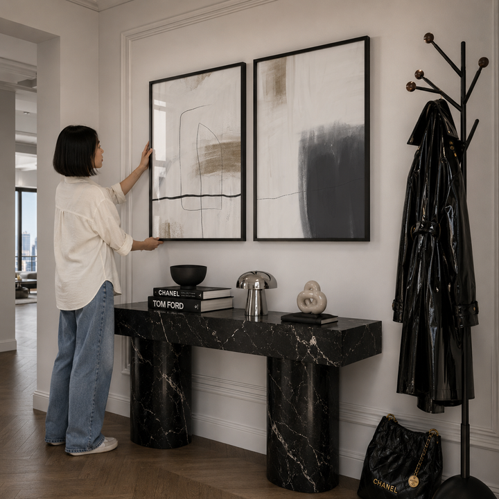 Woman arranging abstract art on a wall in a stylish interior setting.