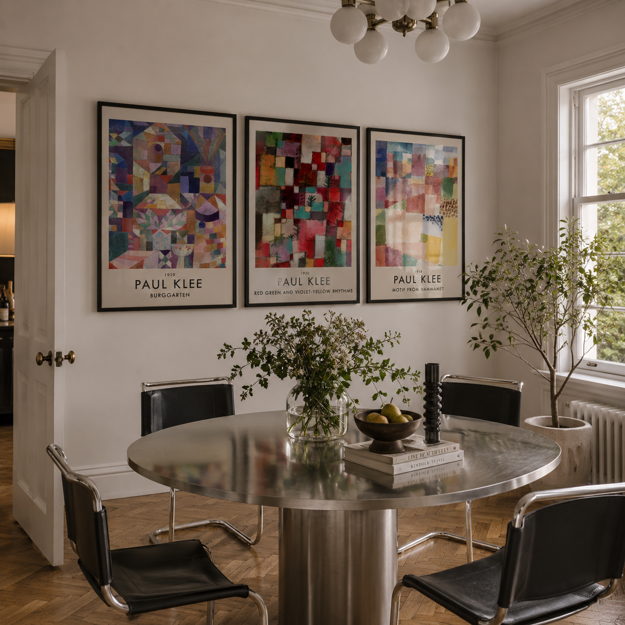 Dining room with a round table, chairs, and wall art of Paul Klee's works.