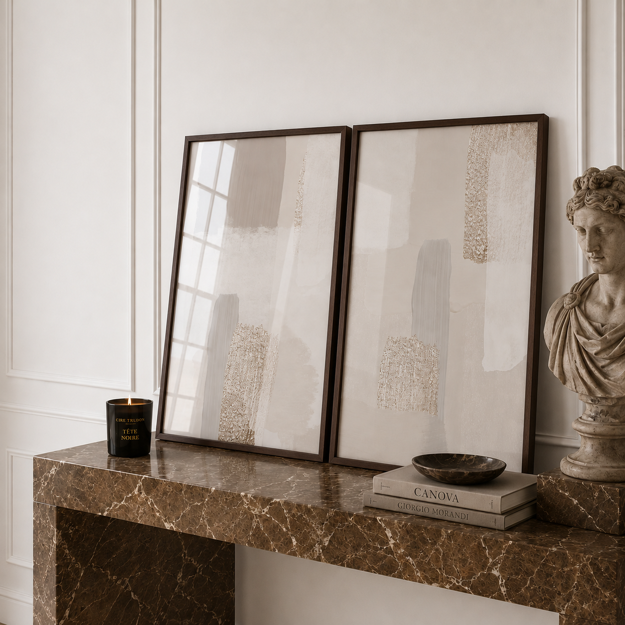 Two framed artworks on a marble console table with decorative items.