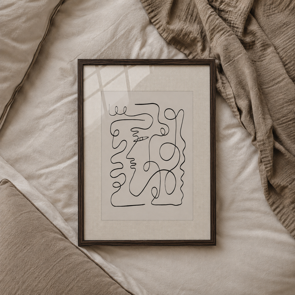 Framed abstract line art on a textured surface with a blanket
