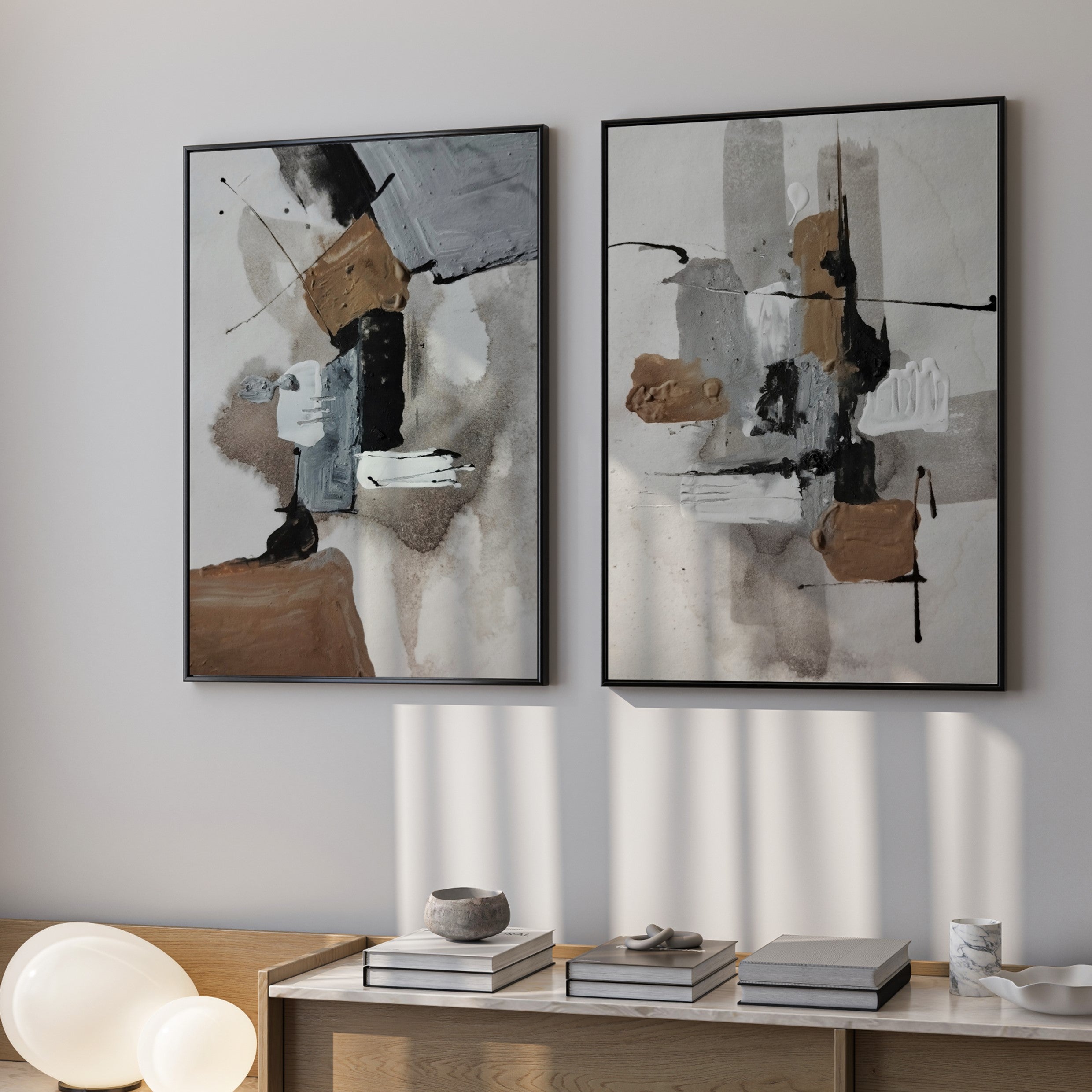 Two abstract art pieces hanging on a wall above a wooden console table.