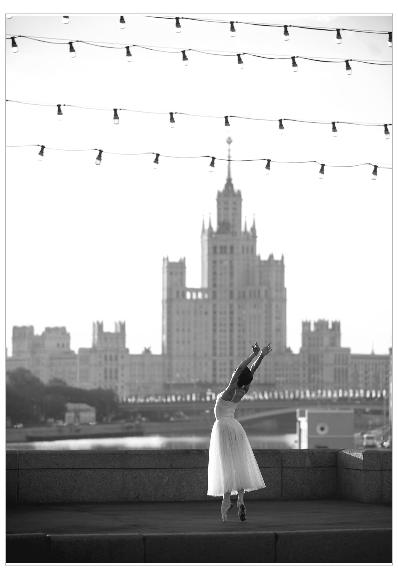 Dancer in a white dress standing on a rooftop with a cityscape in the background
