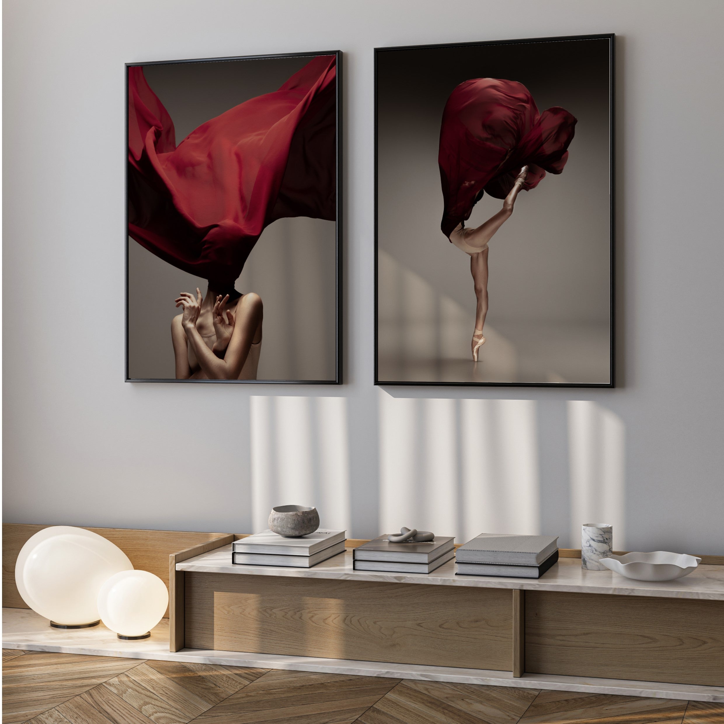 Two framed artworks of a dancer with red fabric on a wall above a wooden console table.