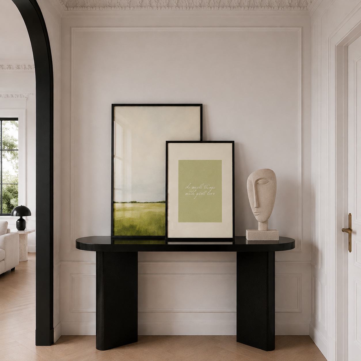 Modern interior with a black console table holding framed artwork and a sculpture.