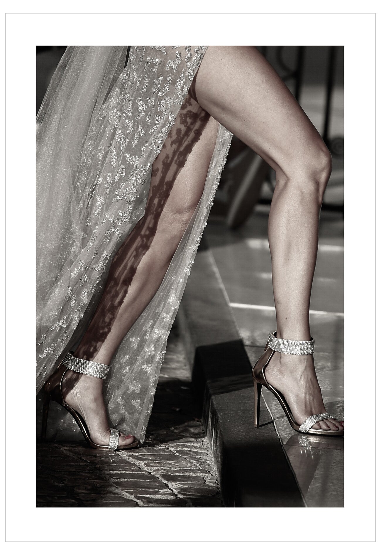 Close-up of a woman's legs wearing high-heeled shoes and a sparkly dress.