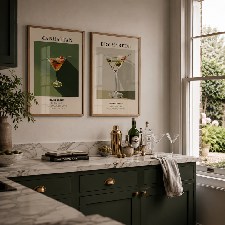 Modern kitchen with marble countertop, green cabinets, and framed cocktail posters.
