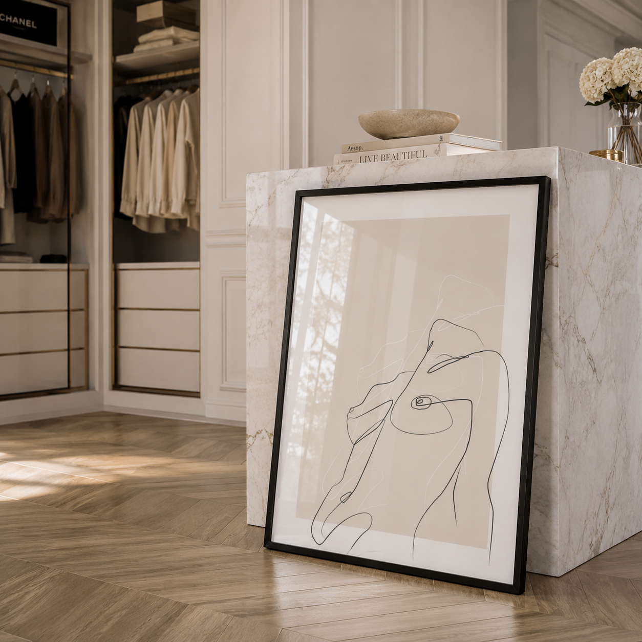 Framed abstract artwork on a marble ledge in a stylish room with clothing and decor.