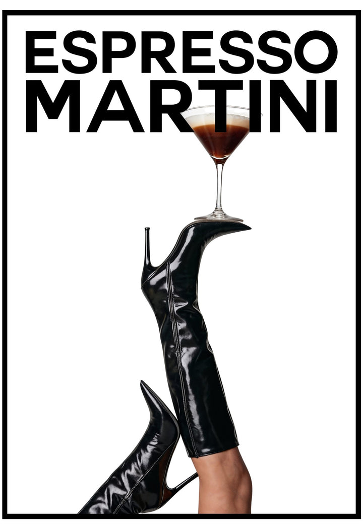 Black high-heeled shoes with a glass of Espresso Martini on a white background